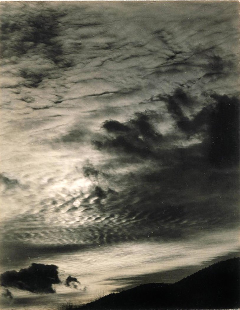 Clouds drifting across a night sky above a dark hillside